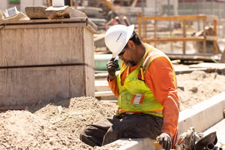 A worker adjusts his helmet on a construction site.