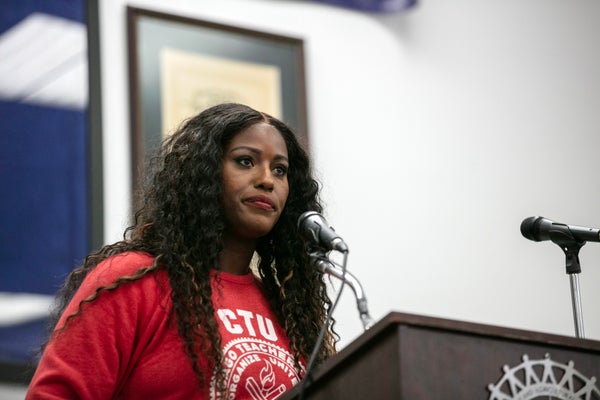 Stacy David Gates in red sweatshirt with CTU Logo speaking at a rally into microphone.