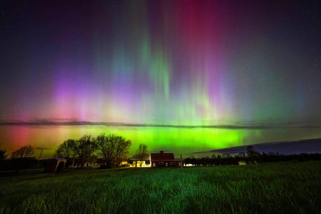 Aurora borealis in the sky over a field and home in Maine, United States