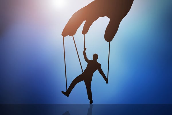 Illustration of silhouetted giant hand controlling a man with puppet strings on a blue background