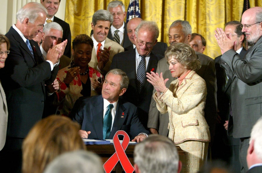 President George W. Bush sits in the East Room of The White House surrounded by bipartisan members of the House and Senate while signing a bill into law