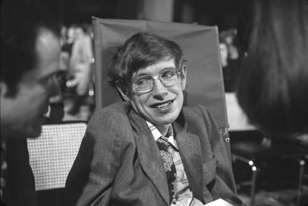 Stephen Hawking seated, smiling, in suit
