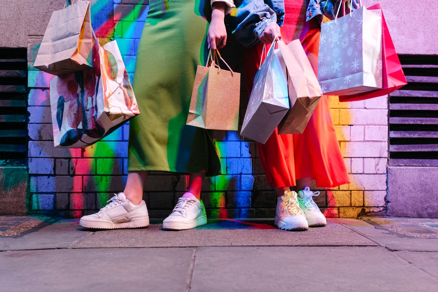 Friends holding shopping bags in front of brick wall