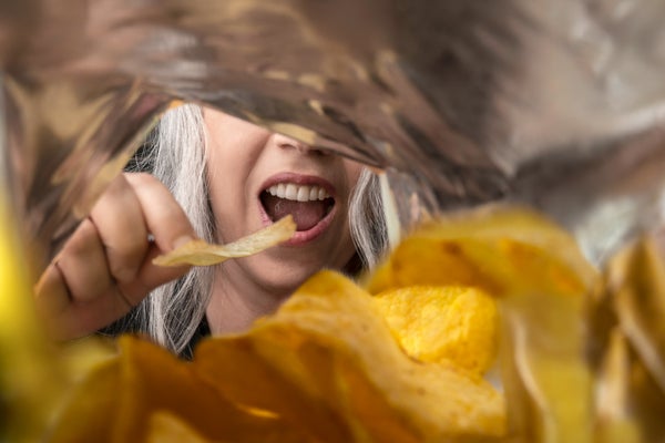 A view of a person eating potato chips from inside the chip foil packaging