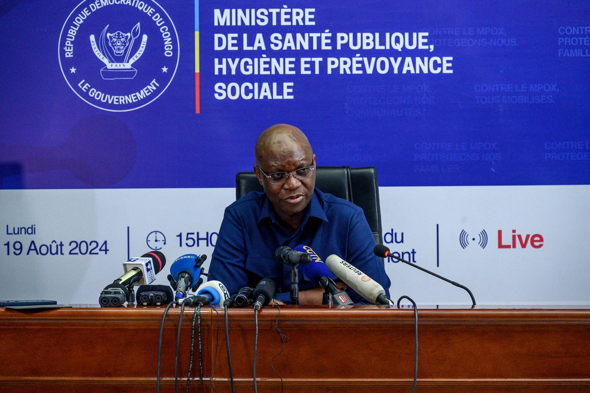 Democratic Republic of Congo Health minister Samuel-Roger Kamba sits at a podium with microphones during a press conference