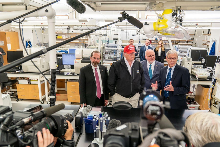 President Donald Trump joined by the Secretary of Health and Human Services Alex Azar left Dr. Robert R. Redfield director of Centers for Disease Control and Prevention and Dr. Stephan Monroe associate director of the CDC right speaks with reporters, seen in the foreground, during a visit to the Centers for Disease Control and Prevention