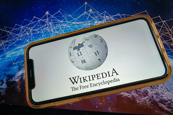 A phone displaying a logo of Wikipedia set against a background alluding to information networks.