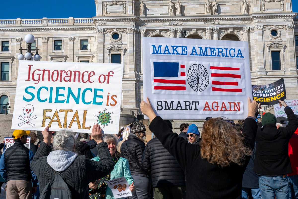 Protesters display signs reading 