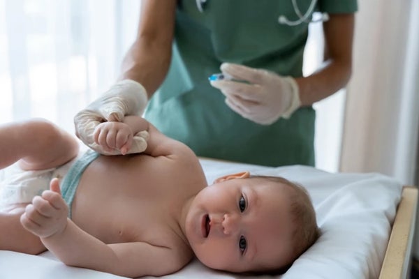 Беба лежи и медицинска сестра даје беби вакцину