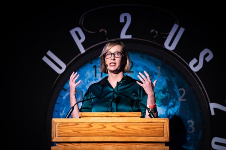 Kate Marvel standing at a podium in front of a large globe.