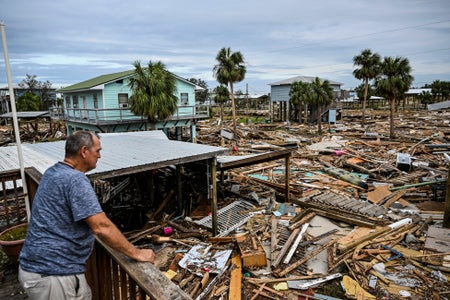 Man looking out to destroyed homes from his deck.