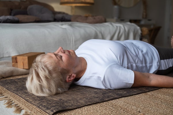 Senior woman laying flat on back on floor in bedroom at home