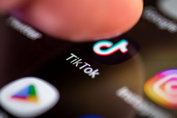 A person pressing on the icon of the social media application TikTok on the screen of a smartphone.