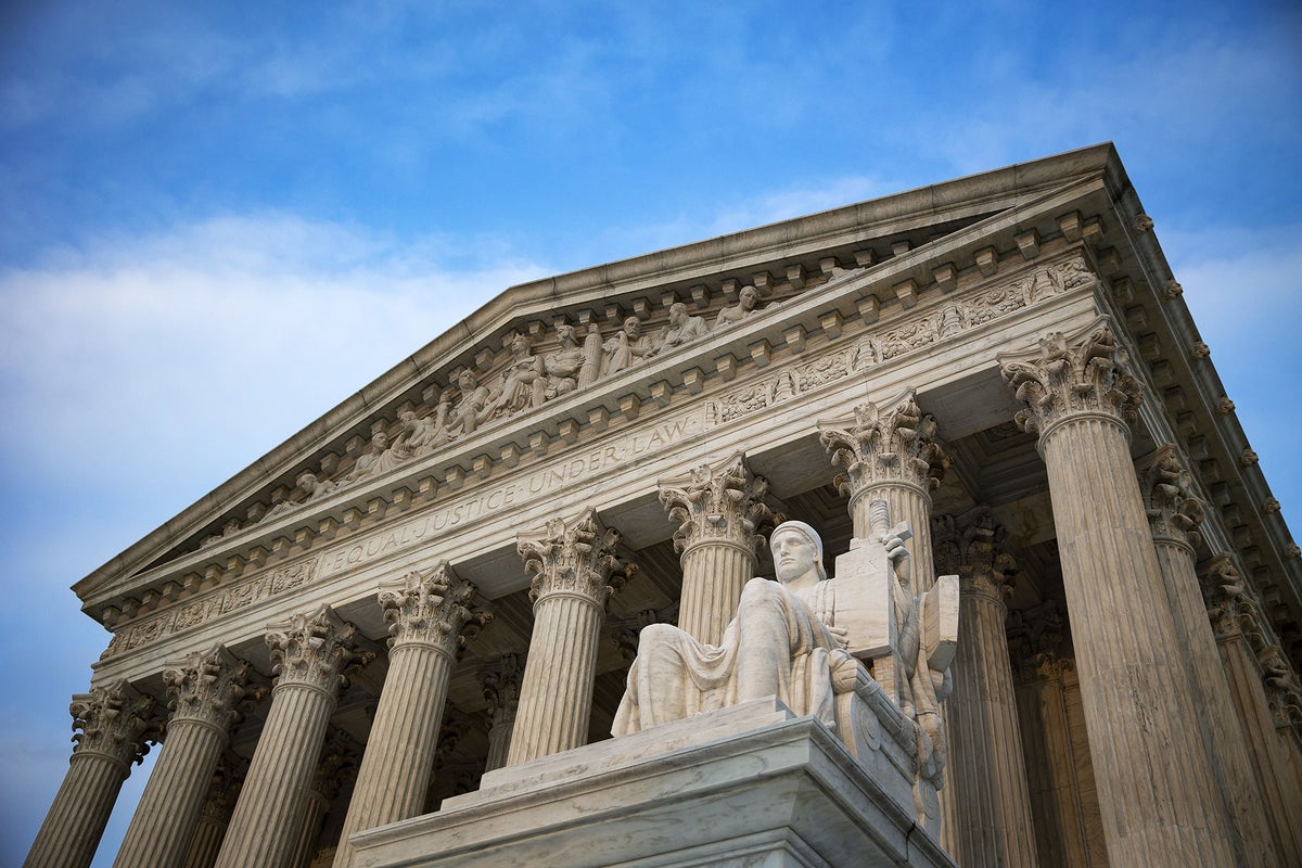 Low angle photograph of the U.S. Supreme Court building in Washington, D.C., with the Authority of Law statue in the foreground
