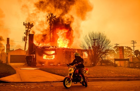 Motorcyclist watches house engulfed by flames