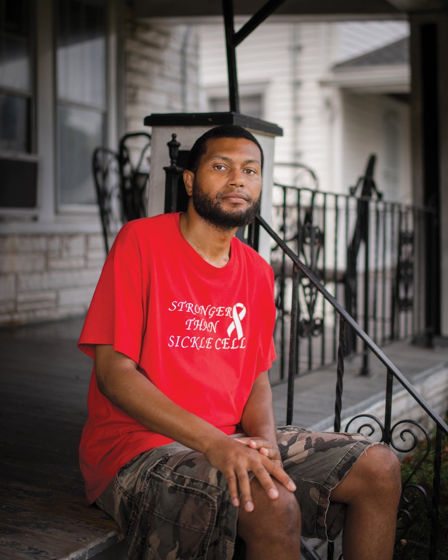 A portrait of a young man sitting on a front porch looking at the camera.