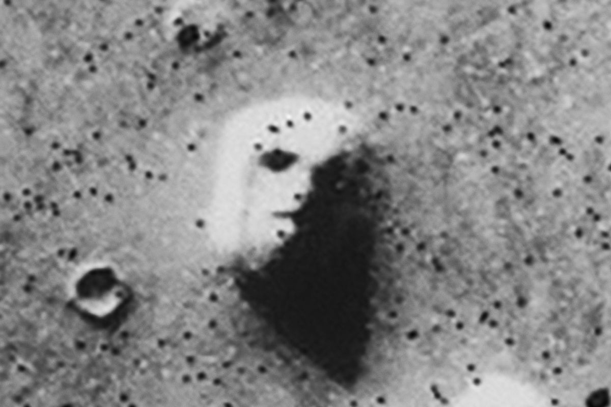 A low resolution image with speckled bit errors captured by NASA's Viking 1 Orbiter spacecraft showing a geological formation on Mars which resembles a face. Bit errors comprise part of one of the 'eyes' and 'nostrils' on the eroded rock that resembles a human face near the center of the image. Shadows in the rock formation give the illusion of a nose and mouth