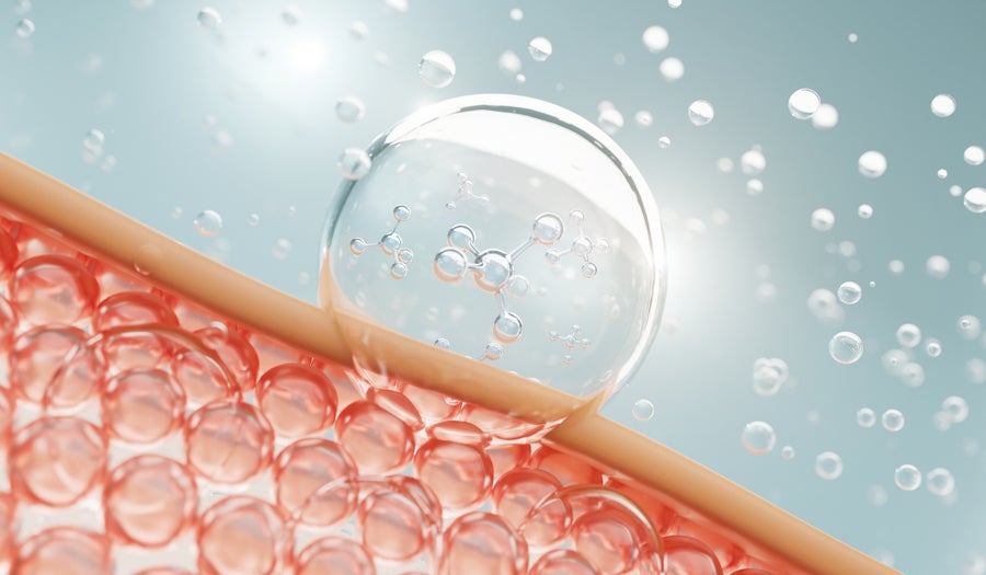 In a computer-generated image visualising skin care, a liquid bubble containing molecules penetrates a skin-like barrier, against a blurred, grey background with more bubbles.