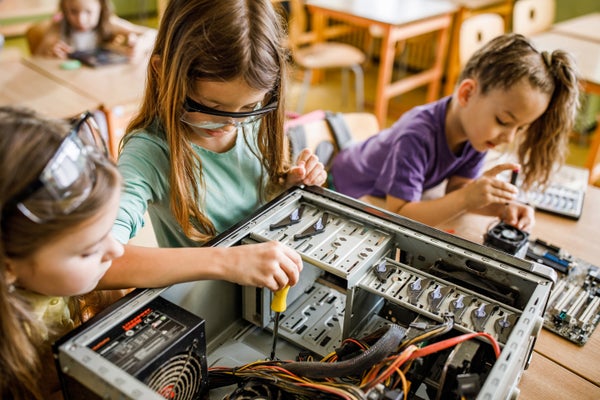 Elementary students cooperating while repairing computer components in the classroom