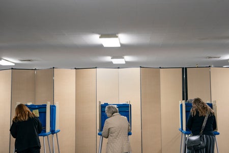 Rear view of three women casting voting ballots.