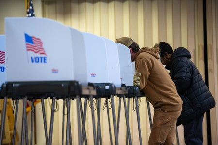 Two voters marking ballots.