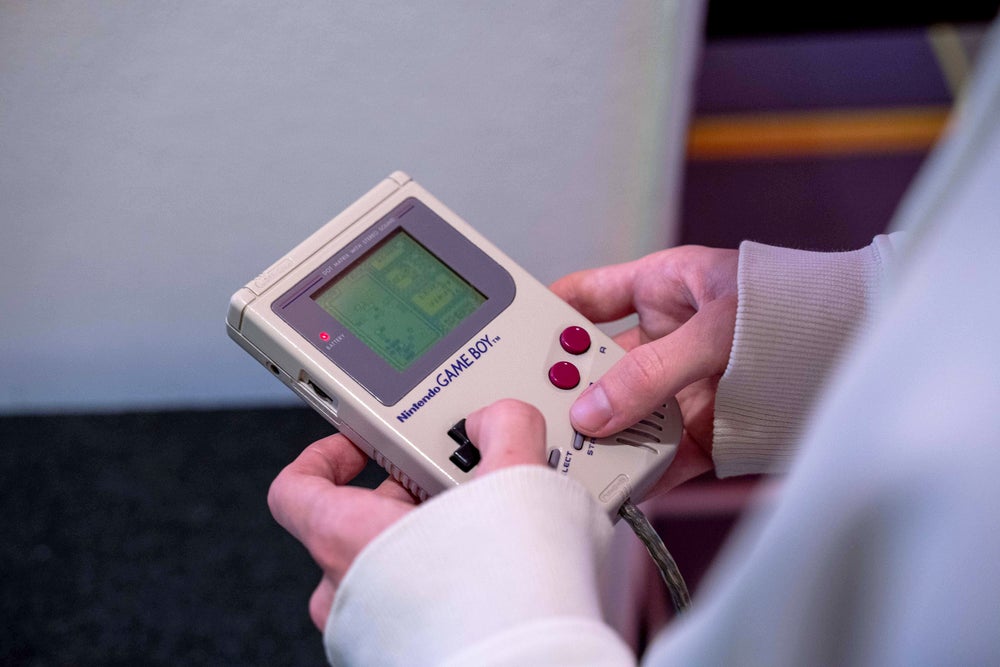 Detalle de la persona que juega Tetris en un dispositivo Nintendo Gameboy