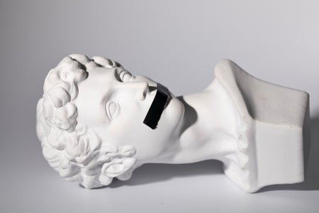 Classical stone sculpture bust portrait laying on its side with black tape over mouth