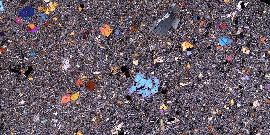 Colorful mineral crystals embedded in translucent volcanic rock slice