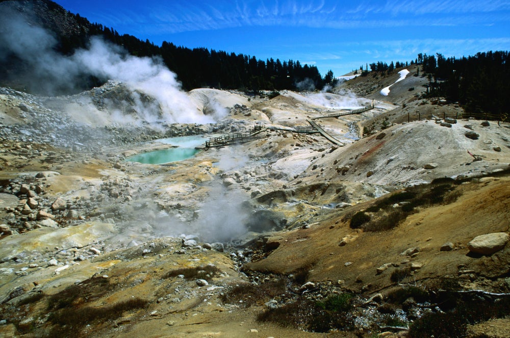 El vapor surge de la tierra amarilla y pardusca y de los estanques geotérmicos de color azul verdoso.
