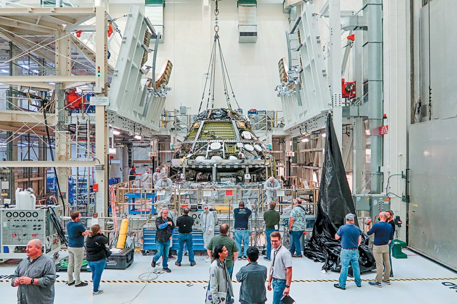 An interview showing large industrial equipment hanging from ceiling with people in the foreground.