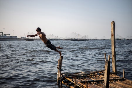 A child jumps off a rickety dock into the ocean