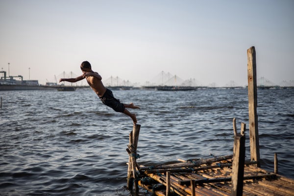 A child jumps off a rickety dock into the ocean