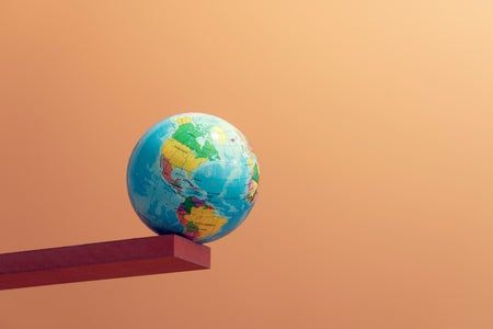 An Earth globe balancing on the edge of a stick, symbolizing climate crisis