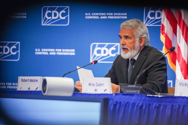 A man speaking into a microphone at a vaccine panel