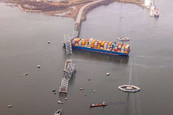 Aerial view of container ship stranded under collapsed bridge after collision