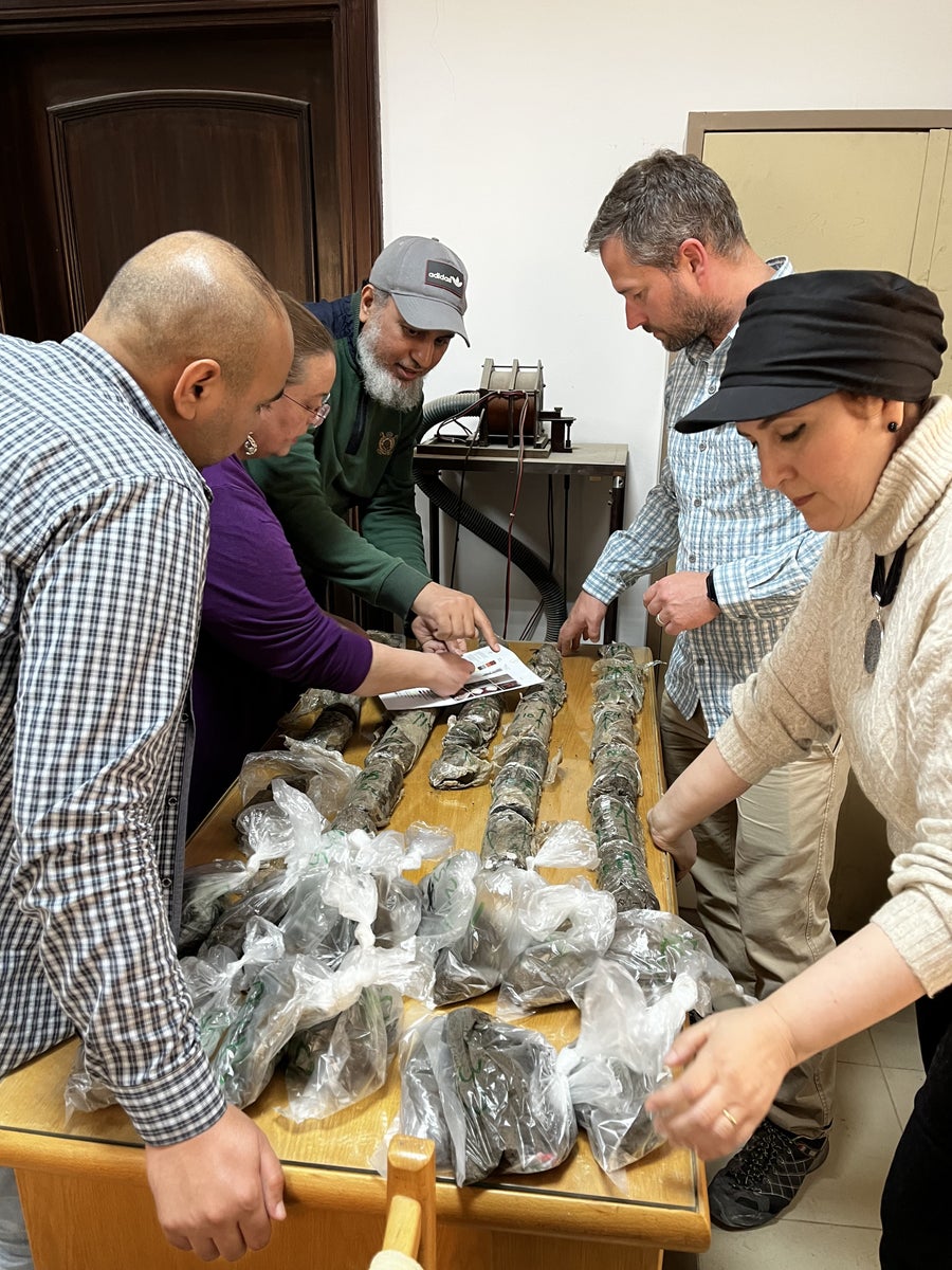 Researchers stand over a table of soil samples wrapped in plastic