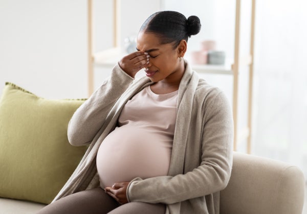 Young pregnant Black woman suffering from headache or migraine