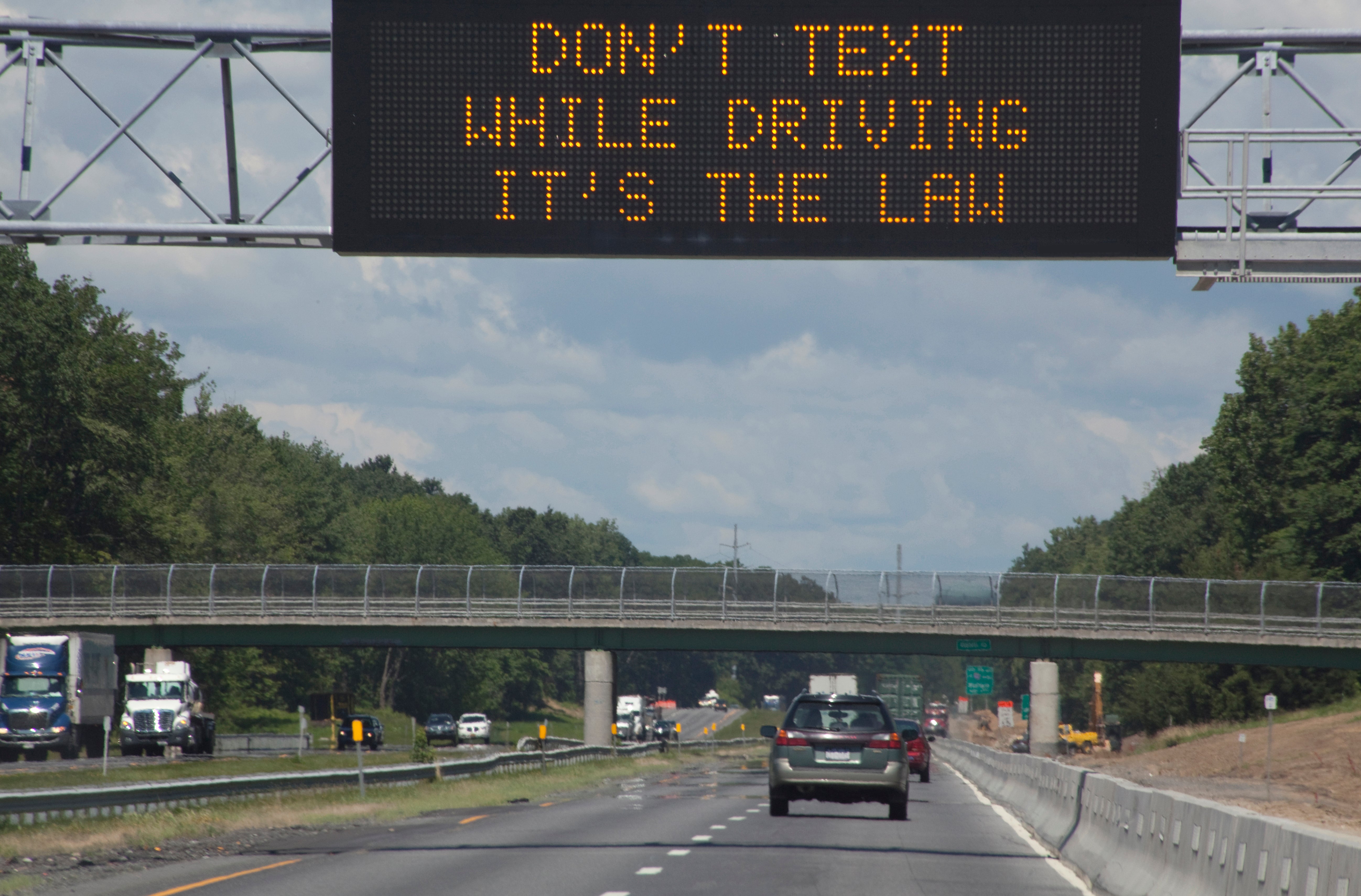 A digital highway sign reads "Don't text while driving it's the law!"