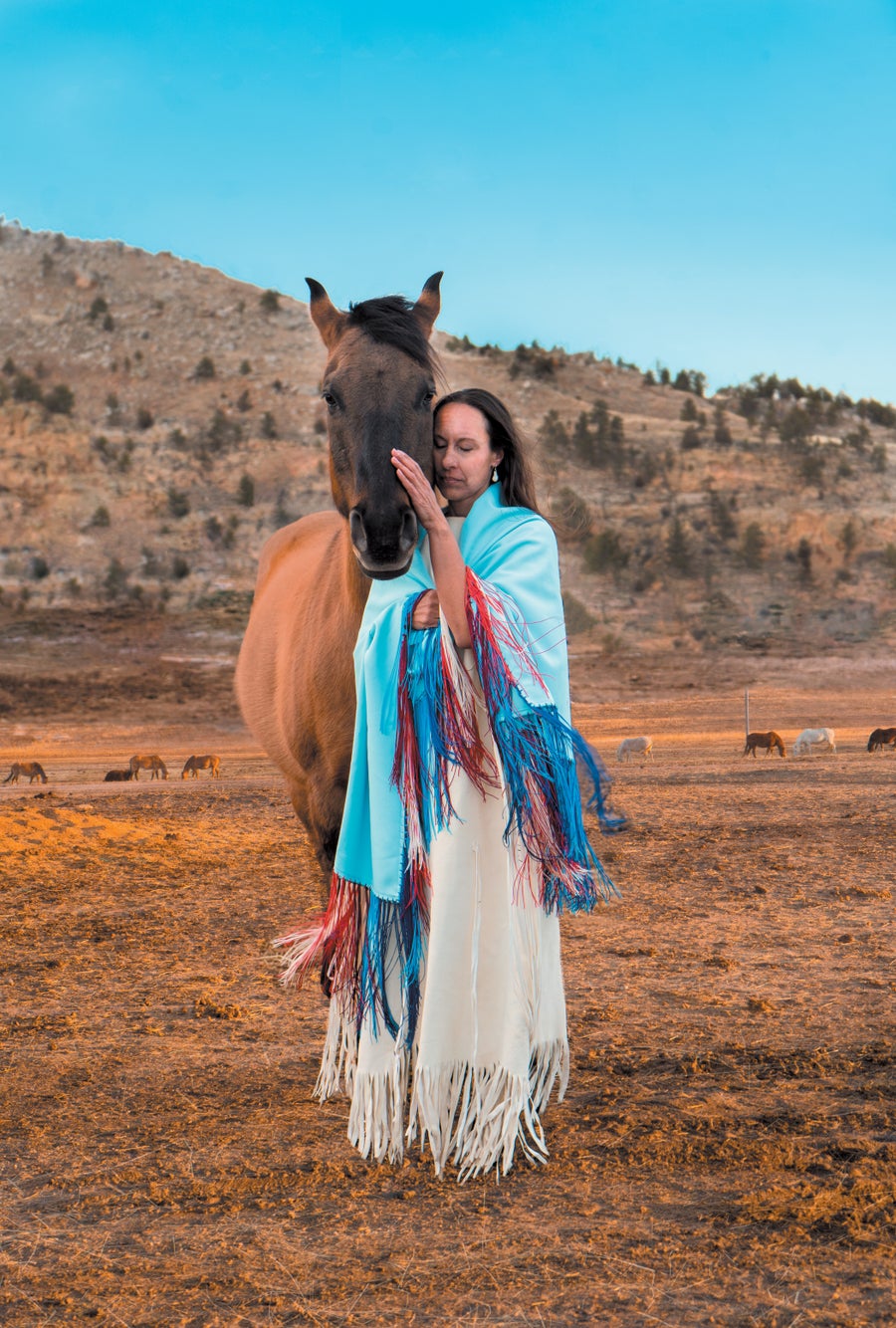 A Native American woman petting a horse outdoors