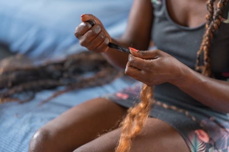 Close-up of hands of an unrecognizable Black woman preparing braids to be put on