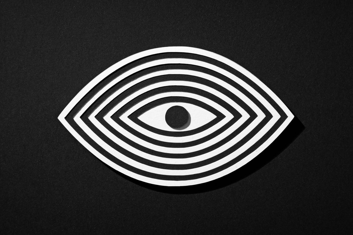 Paper craft cutout of an eye with black and white stripes radiating from the center circle/pupil