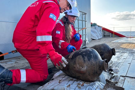 IAA archaeologist Jacob Sharvit, left, and Energean environmental lead Karnit Bahartan examine two Canaanite storage jars after their retrieval from the seafloor of the Mediterranean on May 30, 2024.