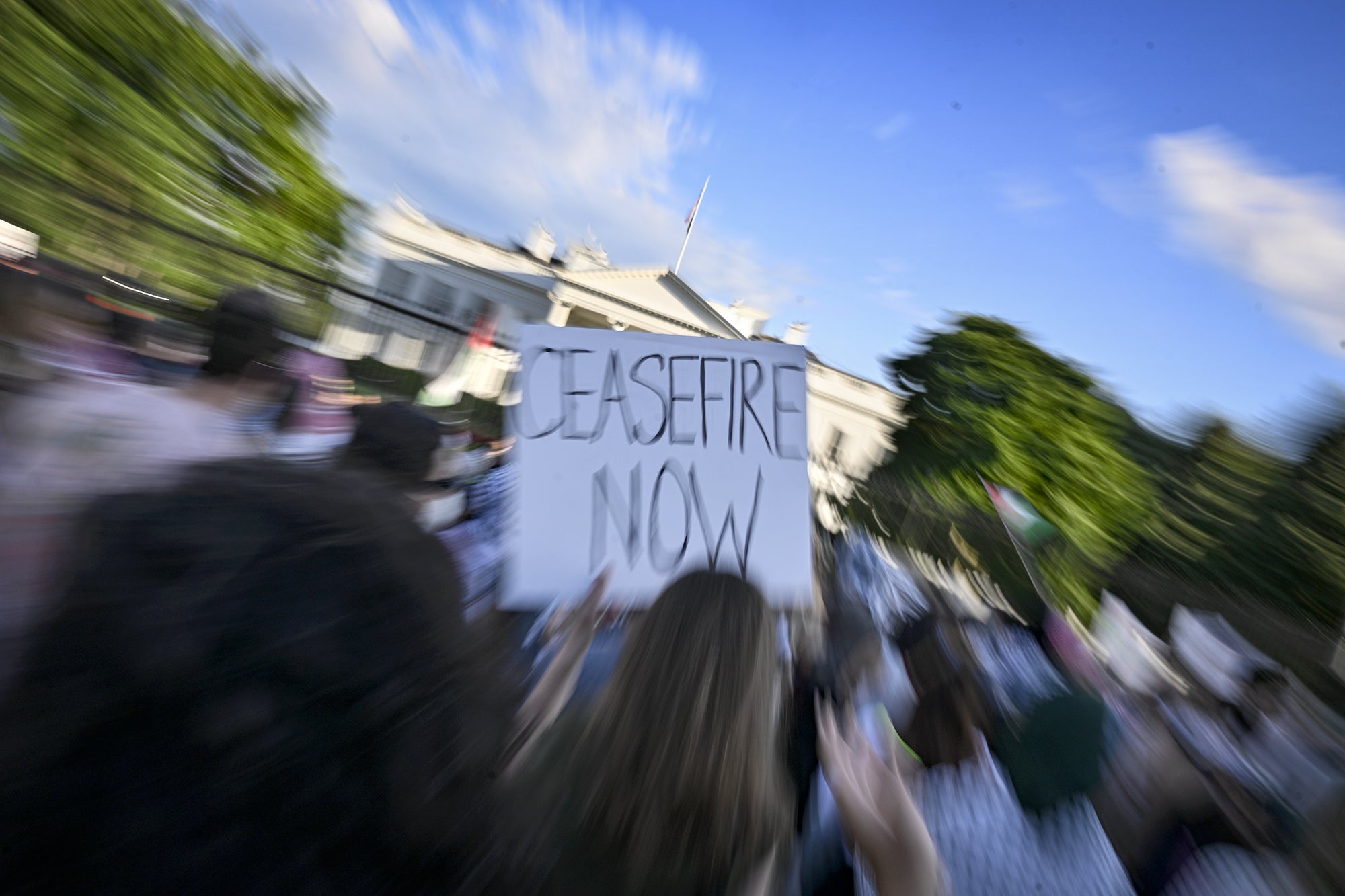 Demonstrators gathered to show solidarity with Palestinians in front of the White House in Washington DC, United States on May 28, 2024. The photographer has used a longer exposure while zooming in on a sign that reads, "Ceasefire now," to create a motion blur effect