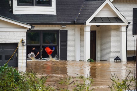 People toss buckets of water out of a home during hurricane Helene.