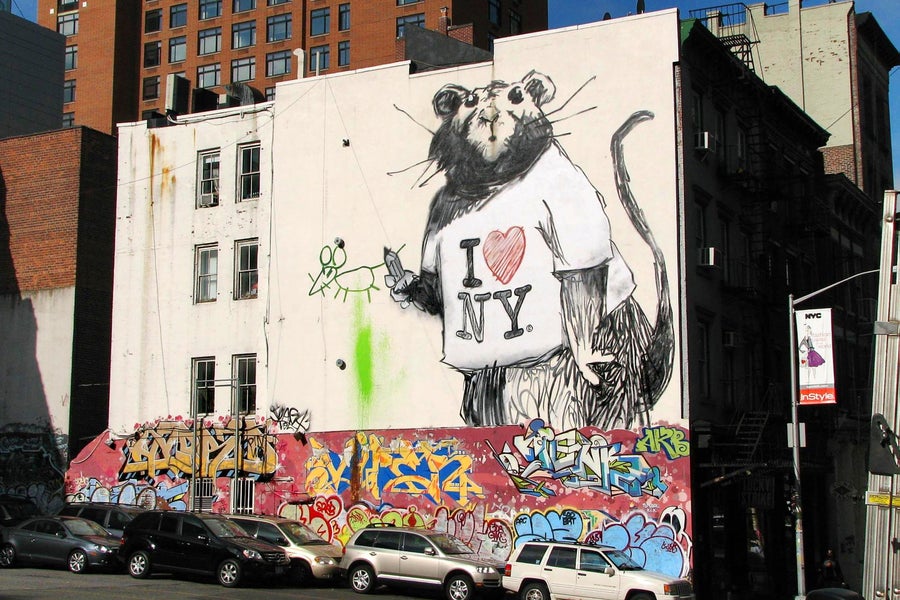 A large mural of a rat wearing an "I Love New York" t-shirt on a wall on Wooster and Grand Street in New York, NY