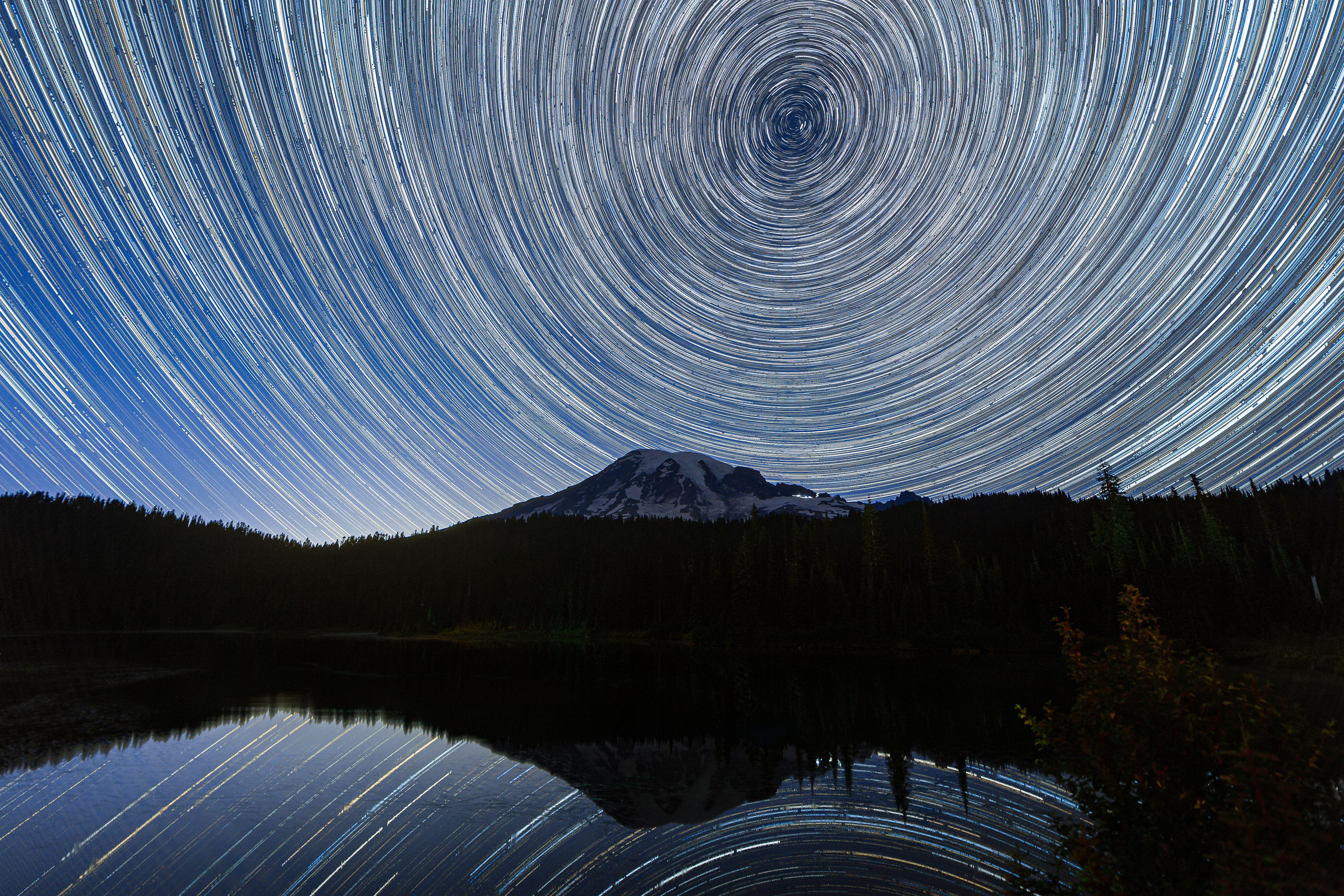 Long exposure photograph showing star trails in the sky over Mount Rainier reflected and mirrored in Reflection Lake in Washington state