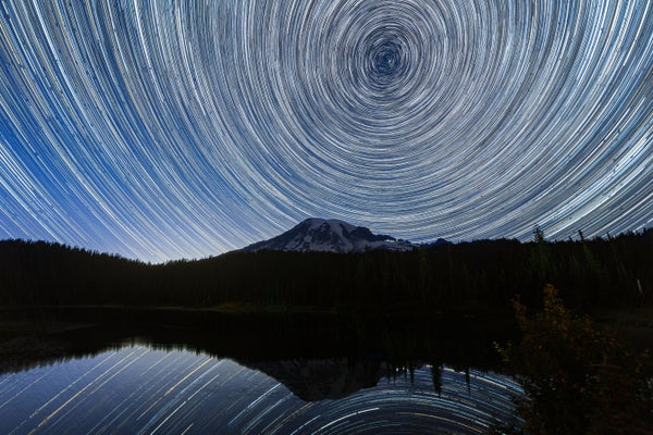Long exposure photograph showing star trails in the sky over Mount Rainier reflected and mirrored in Reflection Lake in Washington state