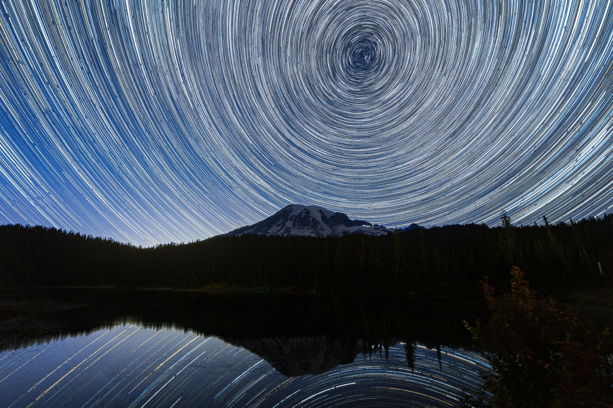 Long exposure photograph showing star trails in the sky over Mount Rainier reflected and mirrored in Reflection Lake in Washington state