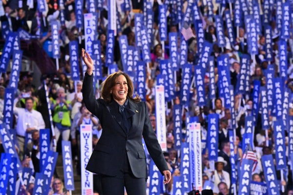 US Vice President and 2024 Democratic presidential candidate Kamala Harris waves on stage with a crowd of supporters holding "Kamala" signs in the background as she arrives to speak at the Democratic National Convention in Chicago, Illinois, on August 22, 2024