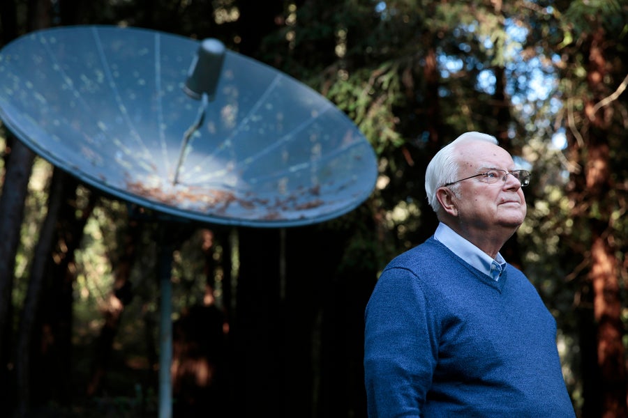 Frank Drake standing in the backyard of his home with a radio dish in the background